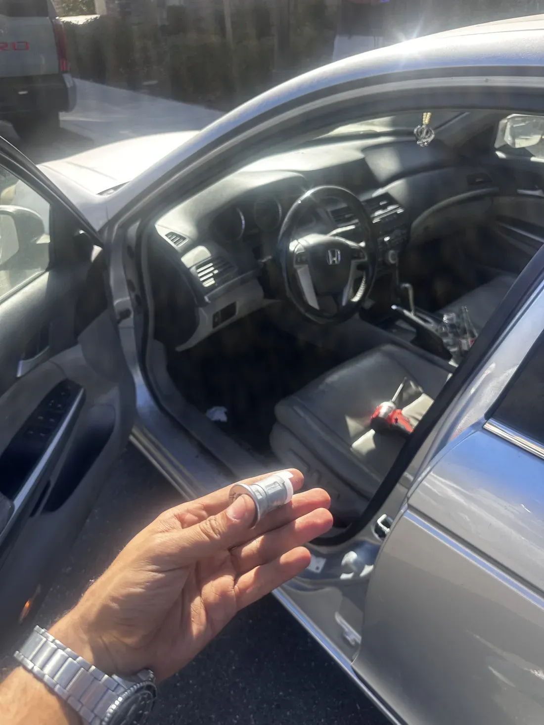 Inside of a car with the driver door open after a lockout, a hand held out toward the cabin