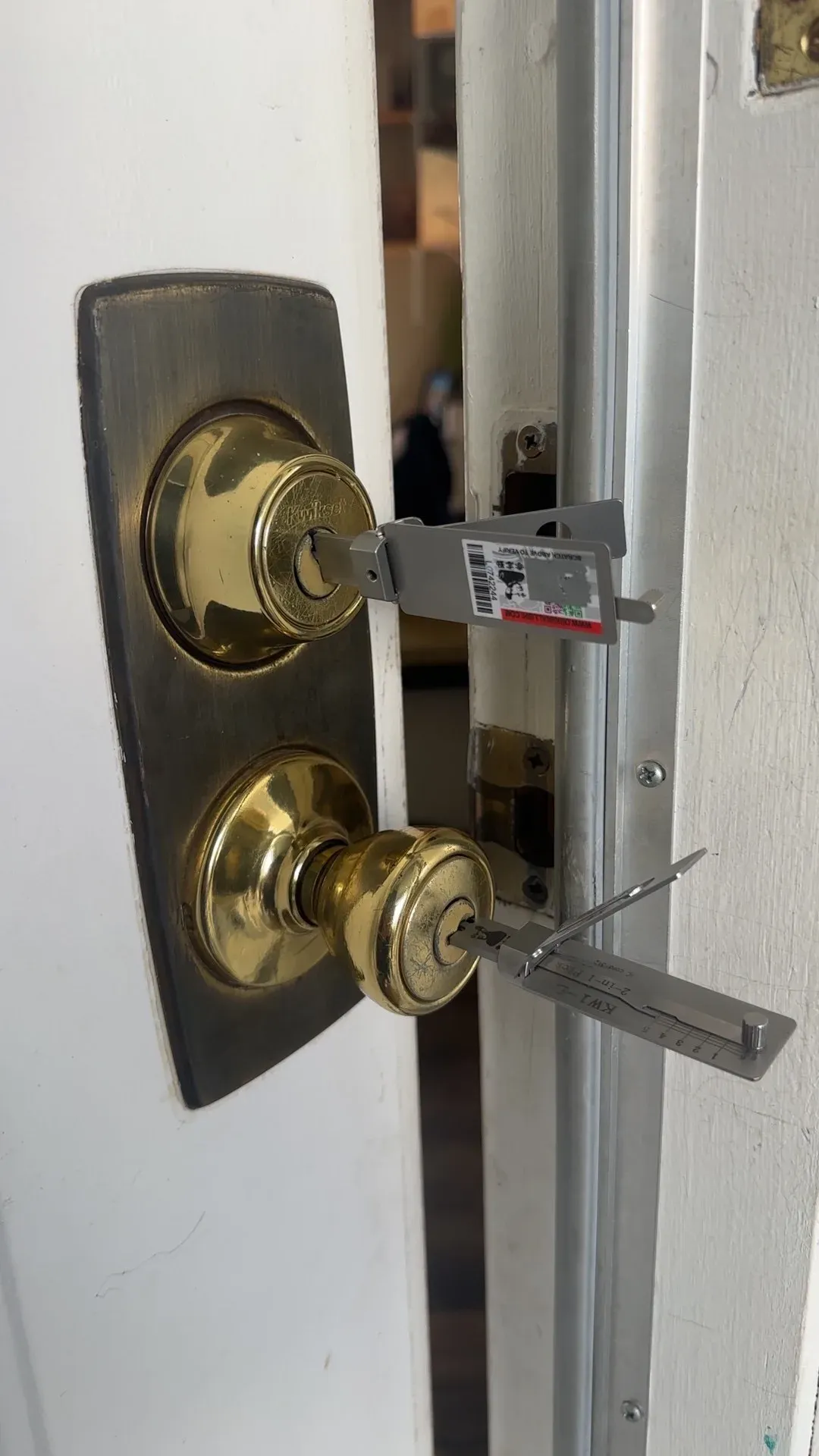 A brass deadbolt and knob on a door with opening tools set into them during a house lockout