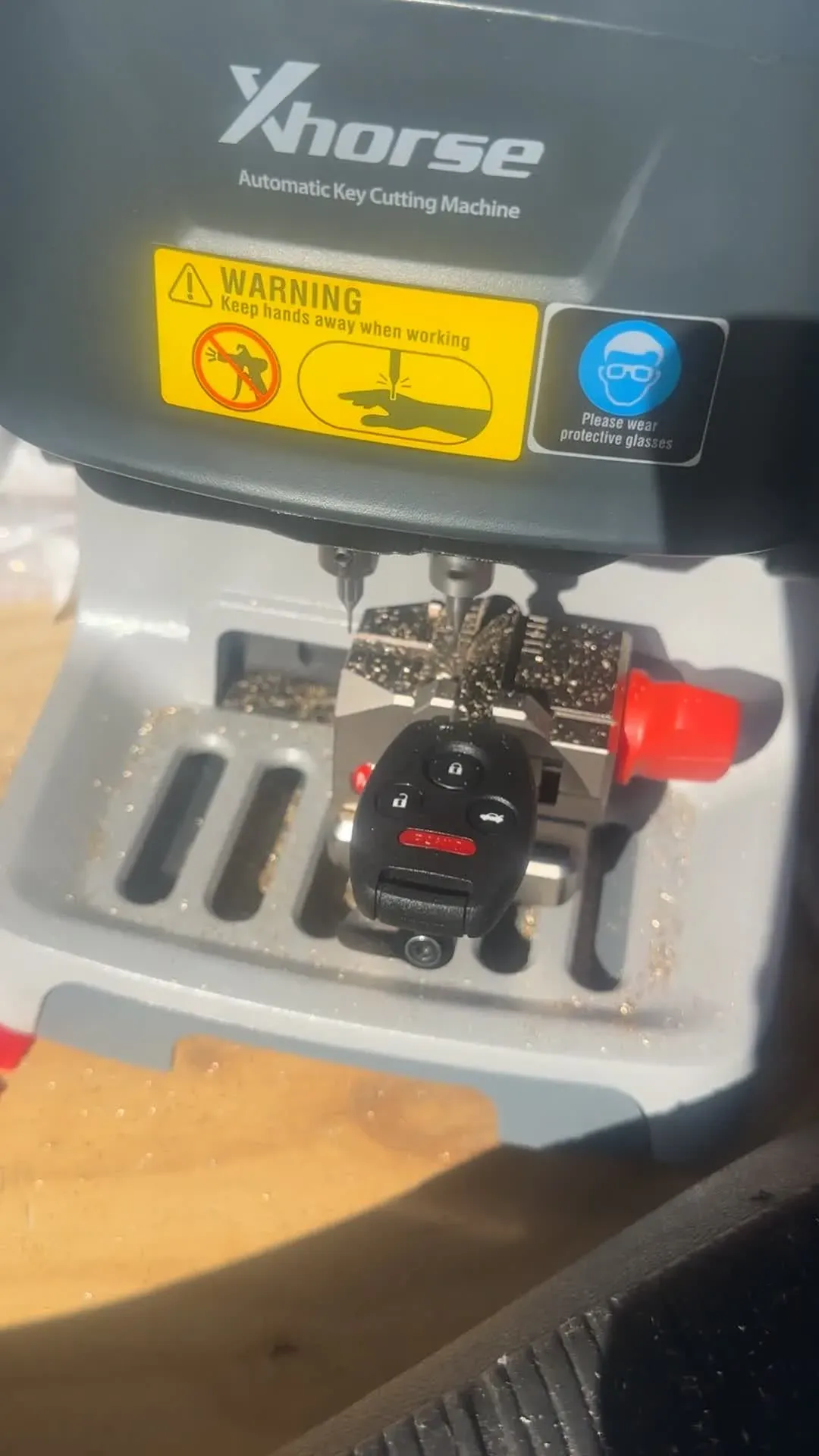 A key cutting machine in a vehicle with a black key fob clamped in place
